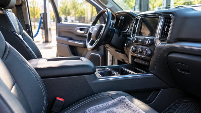 Freshly detailed truck interior with clean black leather seats, a polished dash and console, and a microfiber towel on the passenger seat