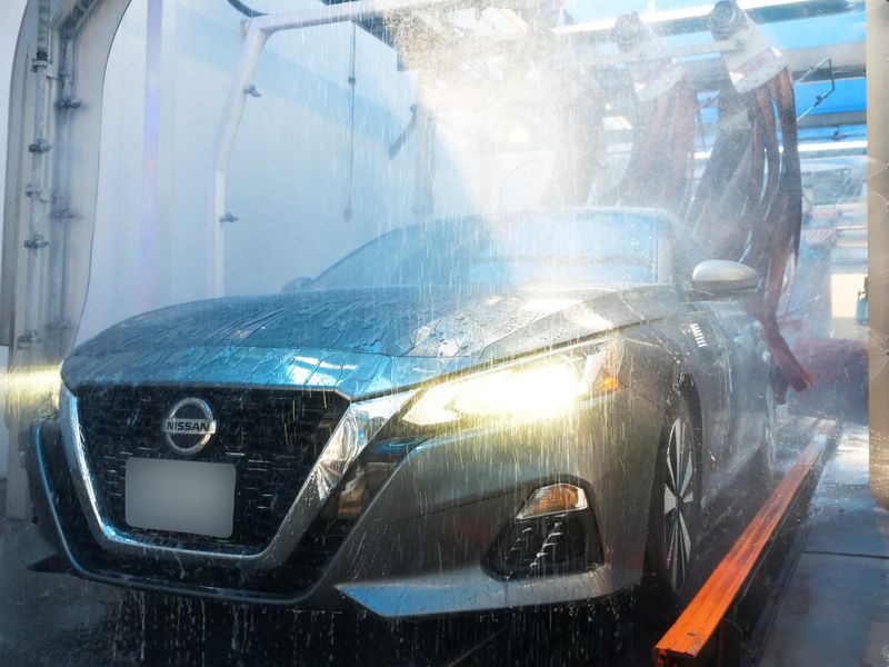 Gray Nissan rolling through the tunnel with water spraying across the hood