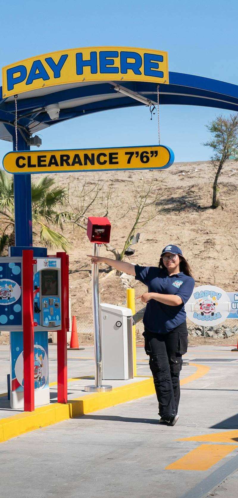 Happy Bubbles team member pointing to the pay station under the Pay Here arch