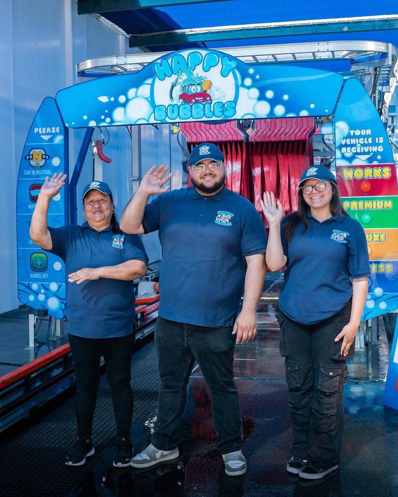 Three Happy Bubbles team members waving under the tunnel arch