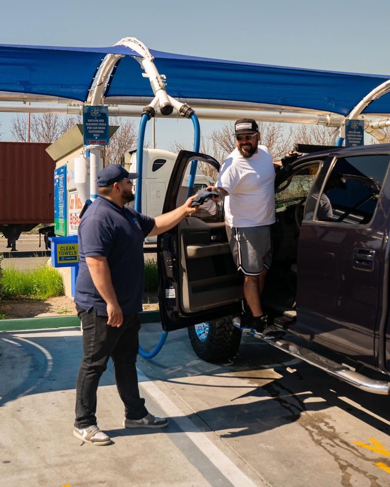 Happy Bubbles team member handing a clean towel to a smiling customer at the vacuum bays